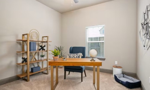 Apartment flex room set up as home office with wood desk and open shelving