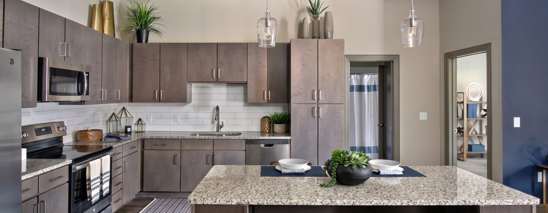 Apartment kitchen with gray-brown cabinets, granite island, and stainless appliances