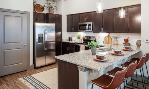 Apartment kitchen with granite island, espresso cabinets, and stainless appliances