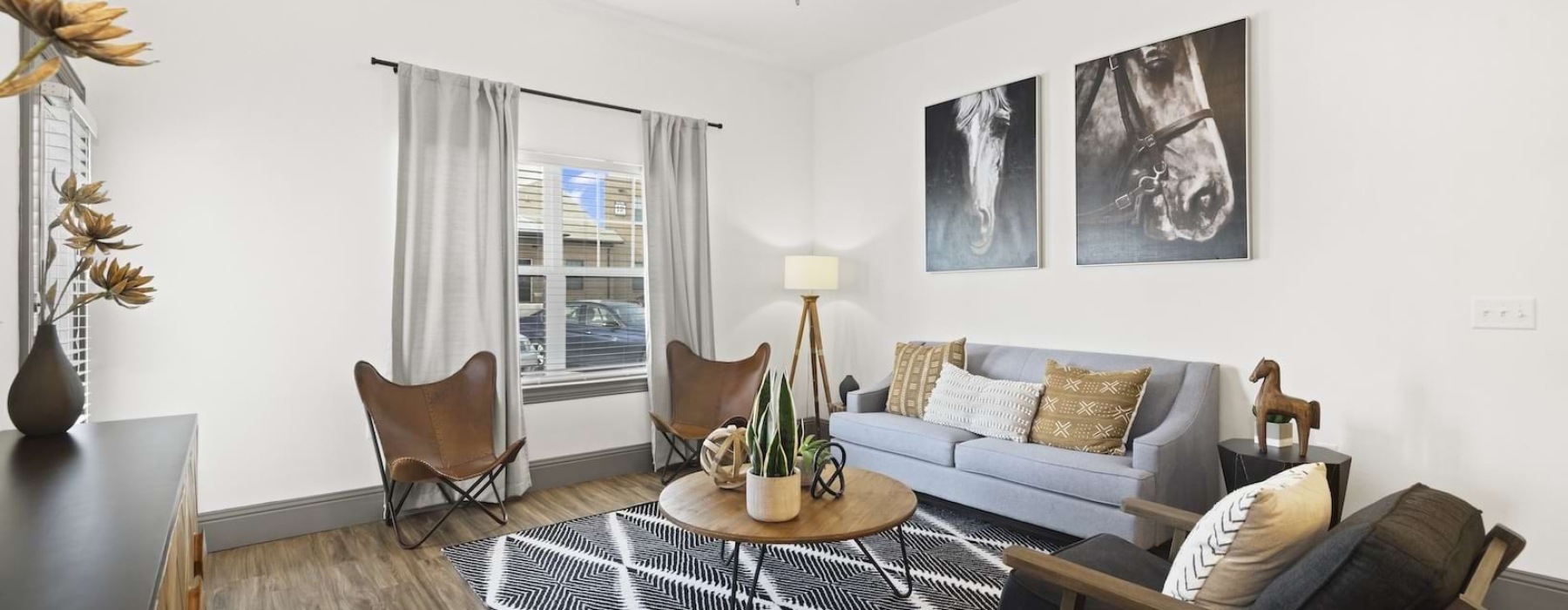 Bright apartment living room with wood floors, gray sofa, and large windows