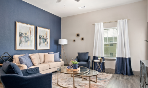 Apartment living room with navy accent wall, cream sofa, and wood-look flooring